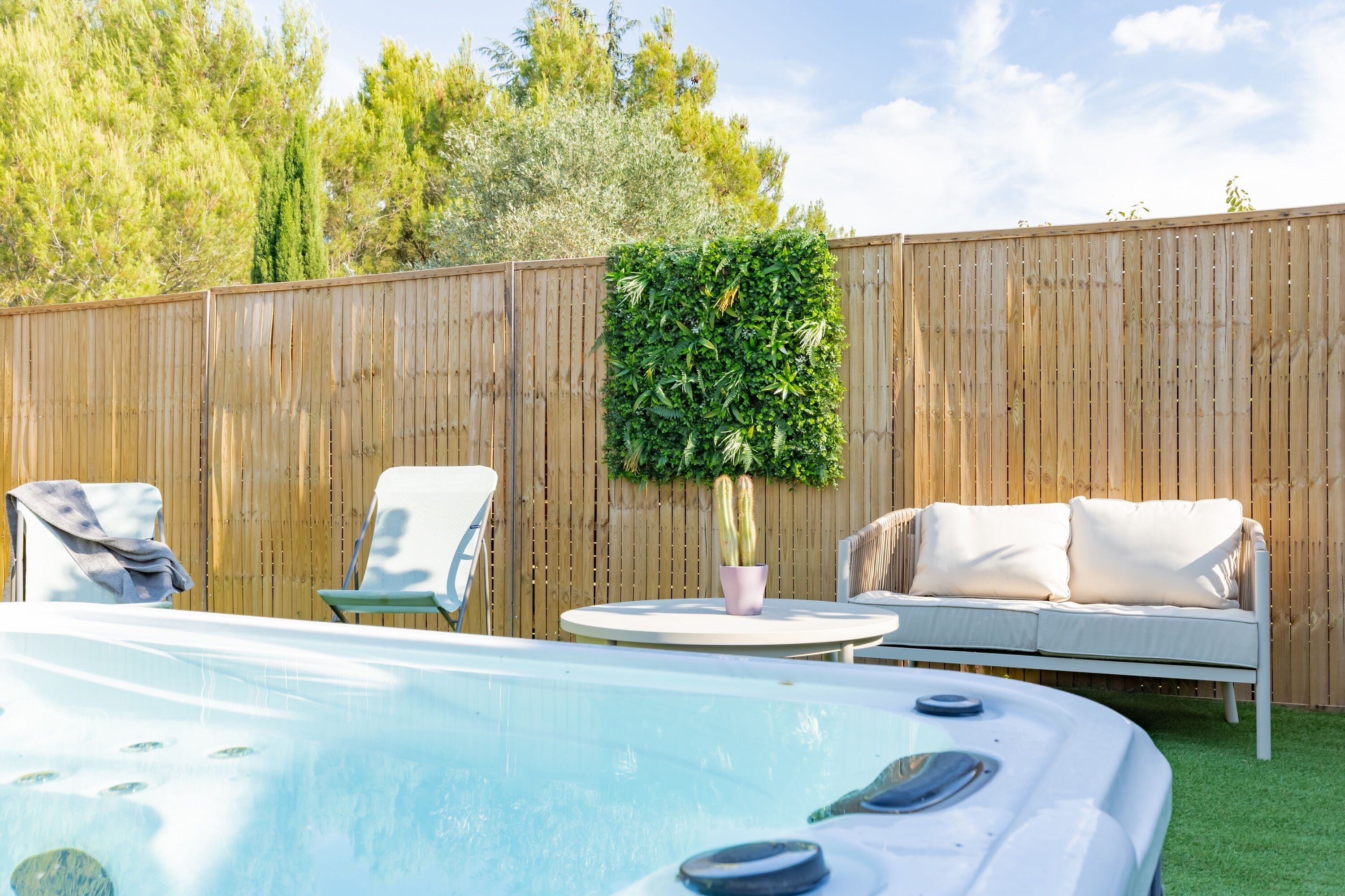 Un jardin avec un jacuzzi, une clôture en bois et du mobilier d’extérieur.
