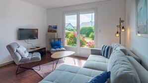 Ein modernes Wohnzimmer mit einer Couch, einem Sessel und einem Flachbildfernseher.