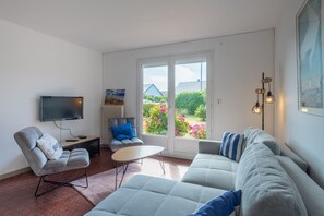 Ein modernes Wohnzimmer mit einer Couch, einem Sessel und einem Flachbildfernseher.