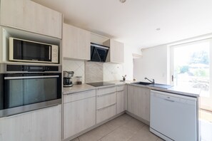 Eine moderne Küche mit integrierten Geräten, einem Geschirrspüler und einem großen Fenster.
