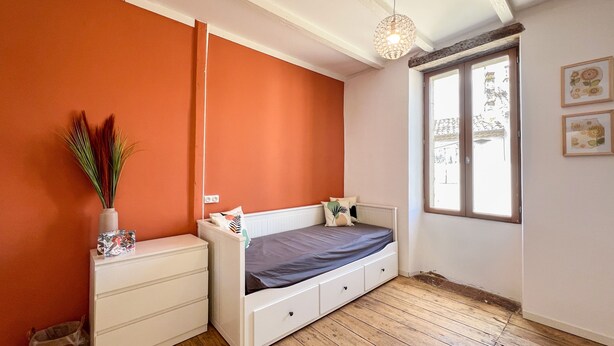 Una camera da letto con un letto, una cassettiera, una finestra e una lampada a sospensione.