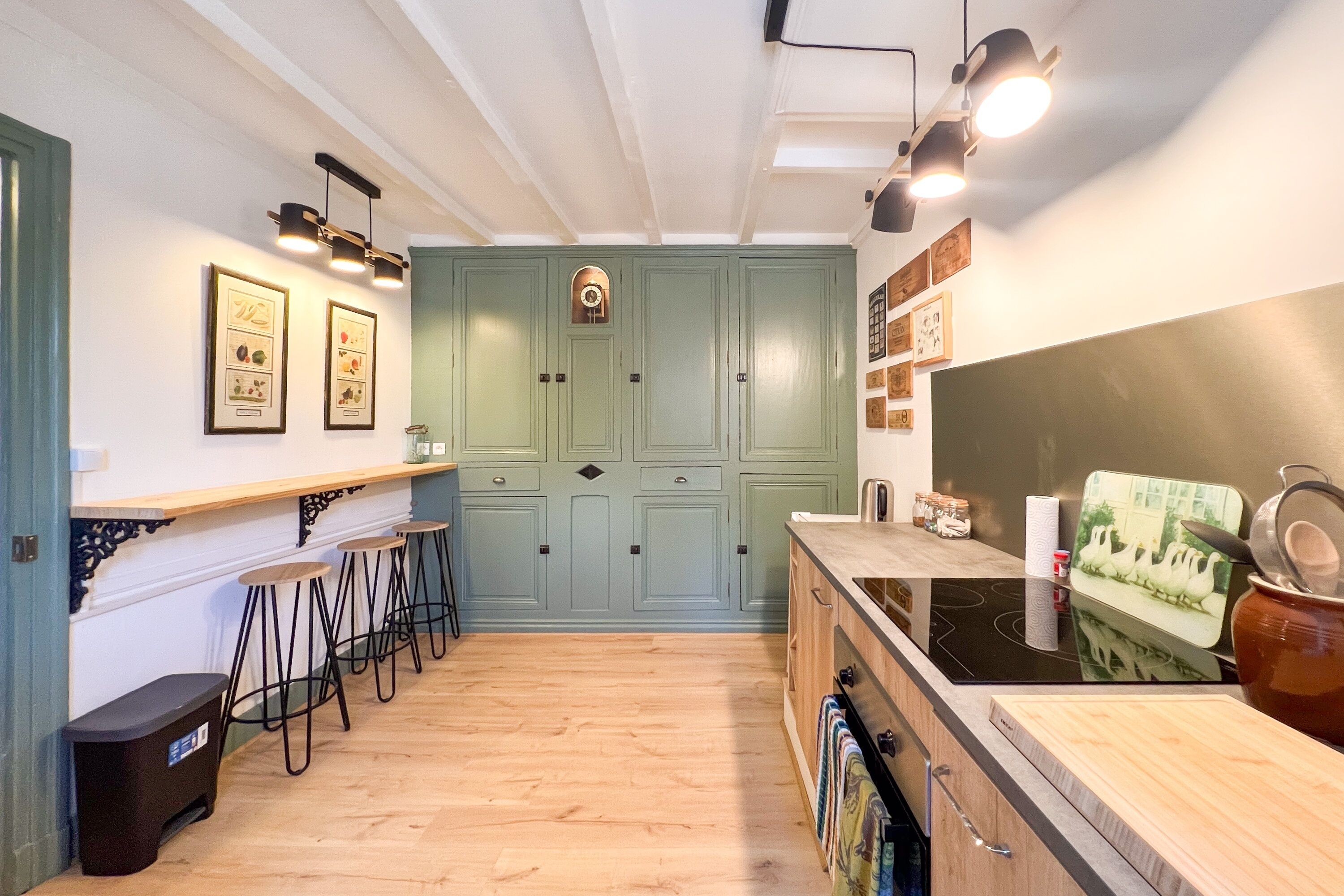 Une cuisine avec un plan de travail en bois, des tabourets de bar, un évier et une cuisinière.