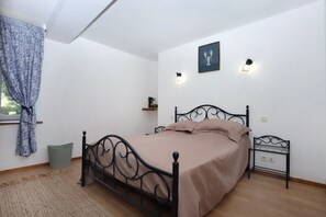A bedroom with a bed, a bedside table, a wall-mounted light, a window with curtains, and a wall decoration. - Au Coeur des Landes Bretonnes - Maison pour 6 (Bains-sur-Oust)