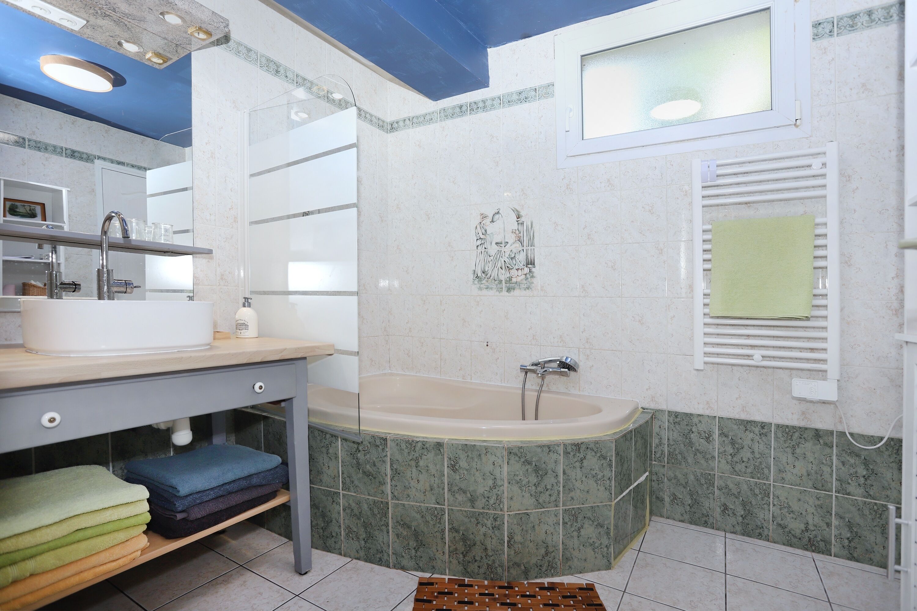 A bathroom with a bathtub, a sink, and a mirror.