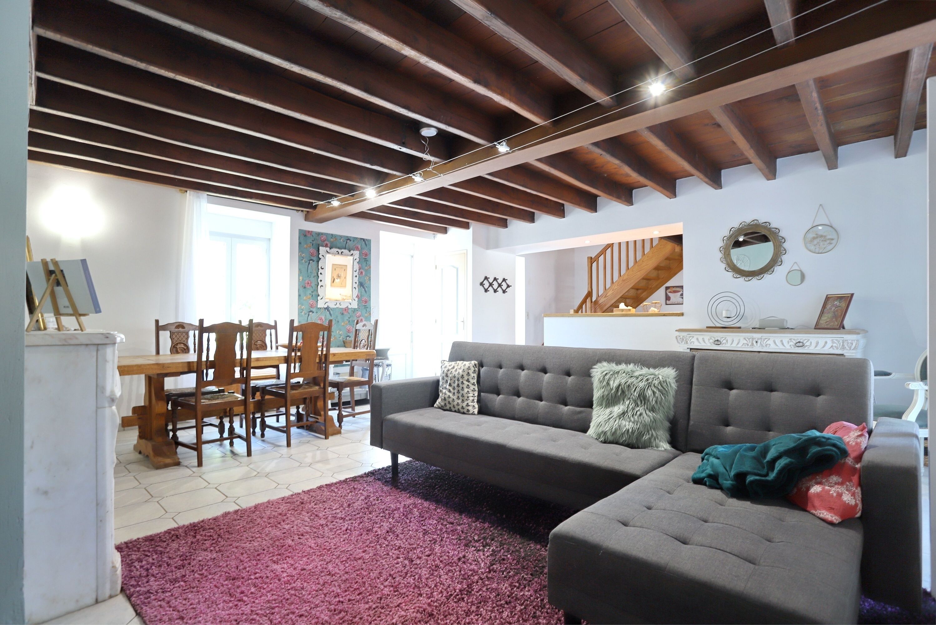 A living room with a grey sofa, wooden dining table, and chairs.