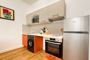 Eine kleine Küche mit Waschmaschine, Backofen und einem FrigluX-Kühlschrank.