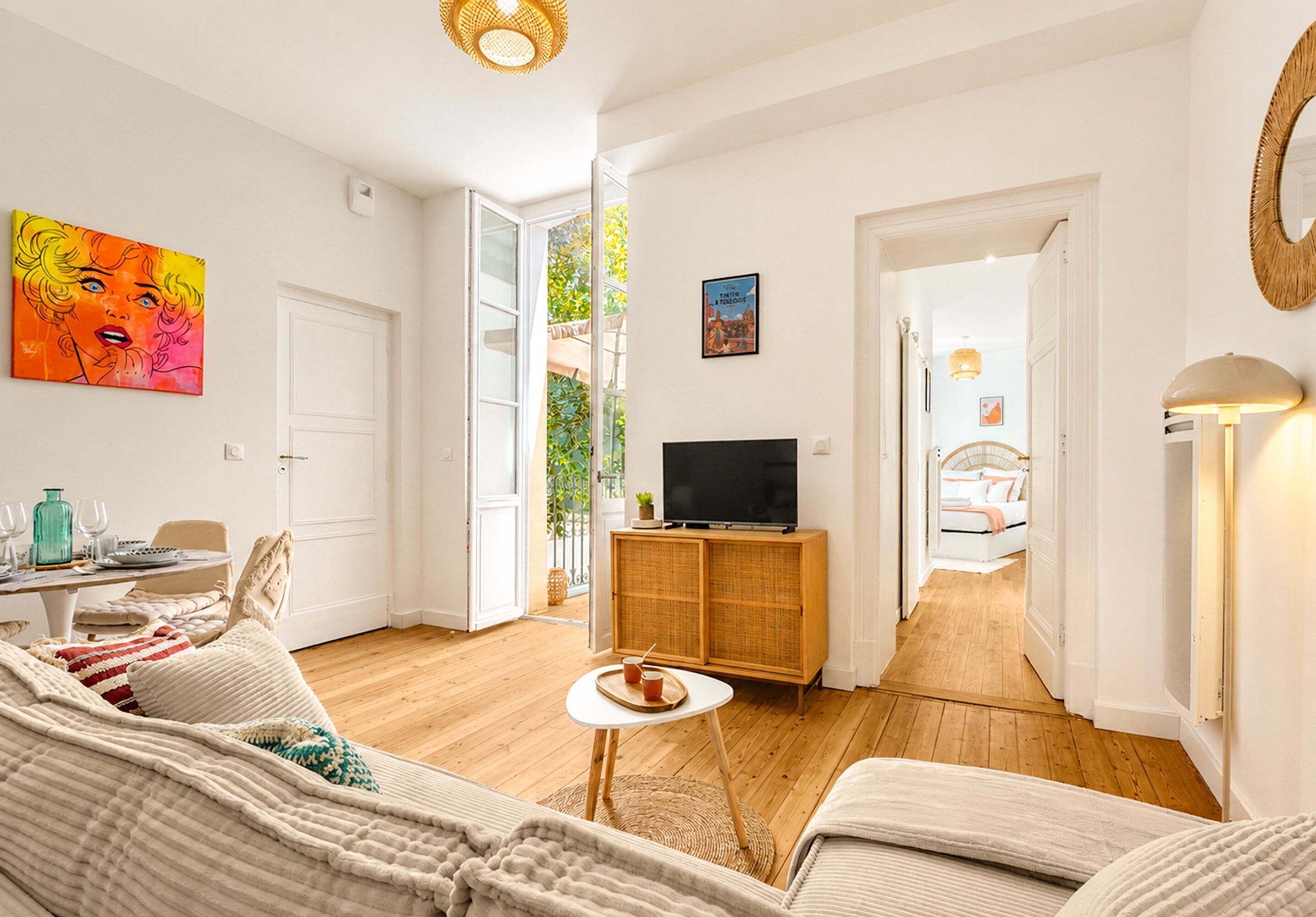 Una sala moderna con un sofá, una mesita, un televisor sobre un mueble de madera y un acceso a otra habitación.