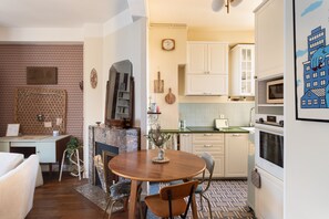A compact kitchen with white cabinets, a wooden dining table, and a patterned floor. - Le Flamand - Appt de charme au centre de Rennes (Rennes)