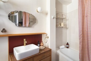 A bathroom with a white sink, a mirror, a towel rack, and a shower curtain. - Le Flamand - Appt de charme au centre de Rennes (Rennes)