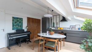 A modern kitchen with a dining area, a piano, and a skylight. - La Casa do pastore - appart sous les toits (Lyon)