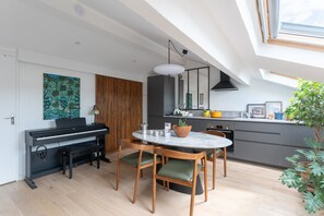 A modern kitchen with a dining area, a piano, and a skylight. - La Casa do pastore - appart sous les toits (Lyon)