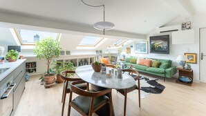 A spacious kitchen with a dining area, a green sofa, and a ceiling fan. - La Casa do pastore - appart sous les toits (Lyon)