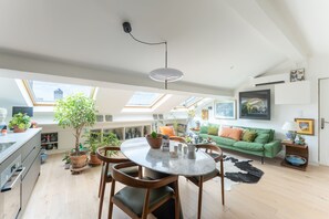 A spacious kitchen with a dining area, a green sofa, and a ceiling fan. - La Casa do pastore - appart sous les toits (Lyon)