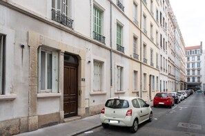 Eine Reihe geparkter Autos an einer Straße mit Gebäuden, die Balkone und Fenster aufweisen.