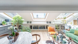 A spacious living area with a skylight, a dining table, a sofa, and various decorative items. - La Casa do pastore - appart sous les toits (Lyon)