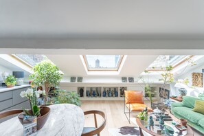 A spacious living area with a skylight, a dining table, a sofa, and various decorative items. - La Casa do pastore - appart sous les toits (Lyon)