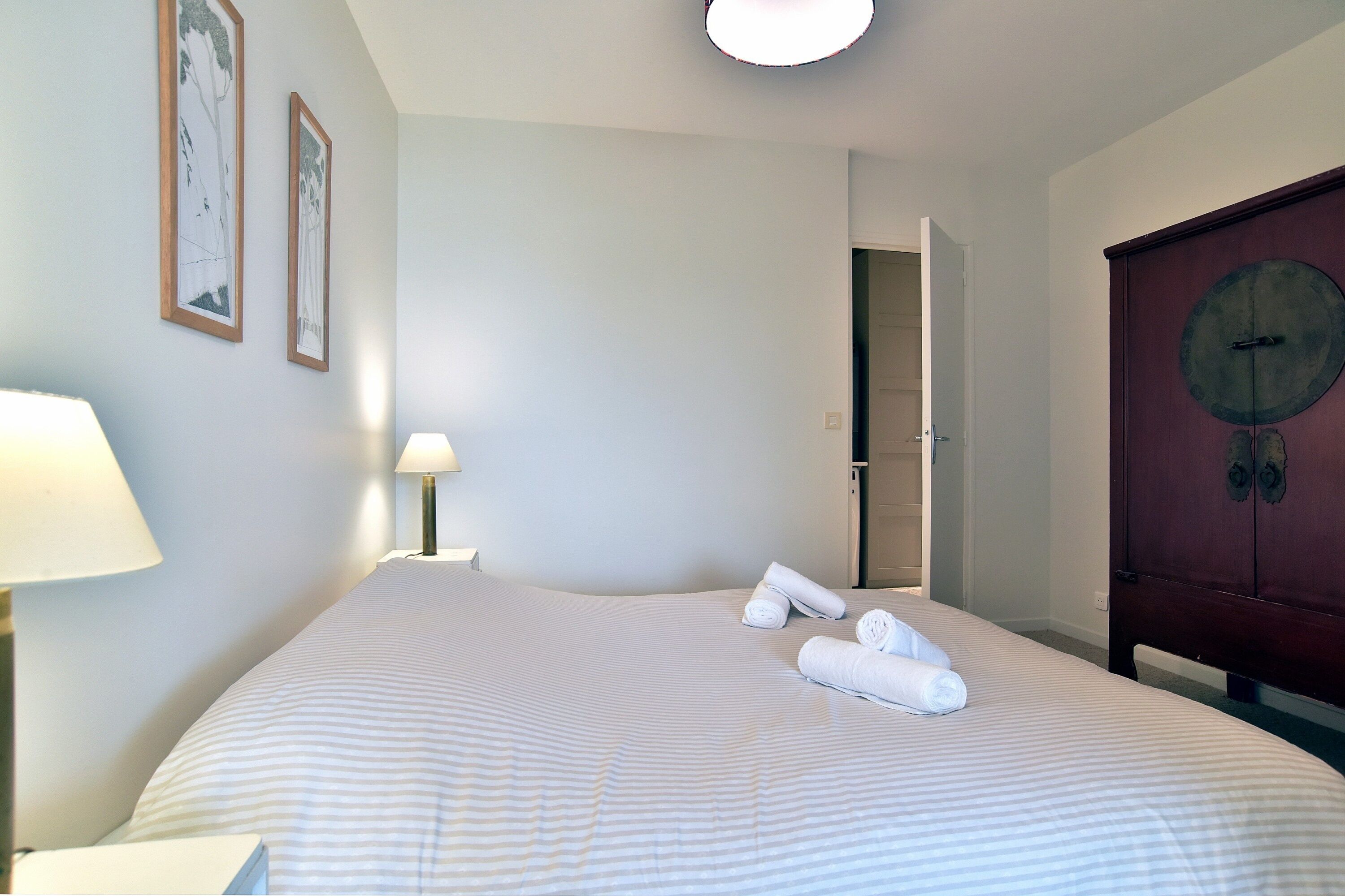 Ein Hotelzimmer mit einem großen Bett, einem Holzschrank und zwei gerahmten Bildern an der Wand.