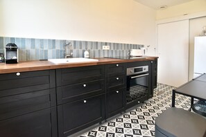 A modern kitchen with a wooden countertop, a sink, and a built-in oven. - L'Aiguillon - À 500 m de la plage (Saint-Cast-le-Guildo)