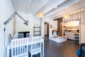 Eine moderne Küche mit einer Wand aus Stein, ein Essbereich mit weißer Möbel und Pendelleuchten.