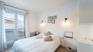 A bedroom with a bed, a nightstand, a wall-mounted shelf, and a window with curtains. - Le Refuge de Saint-Lary - 500m station de ski (Saint Lary-Soulan)