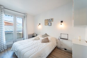 A bedroom with a bed, a nightstand, a wall-mounted shelf, and a window with curtains. - Le Refuge de Saint-Lary - 500m station de ski (Saint Lary-Soulan)