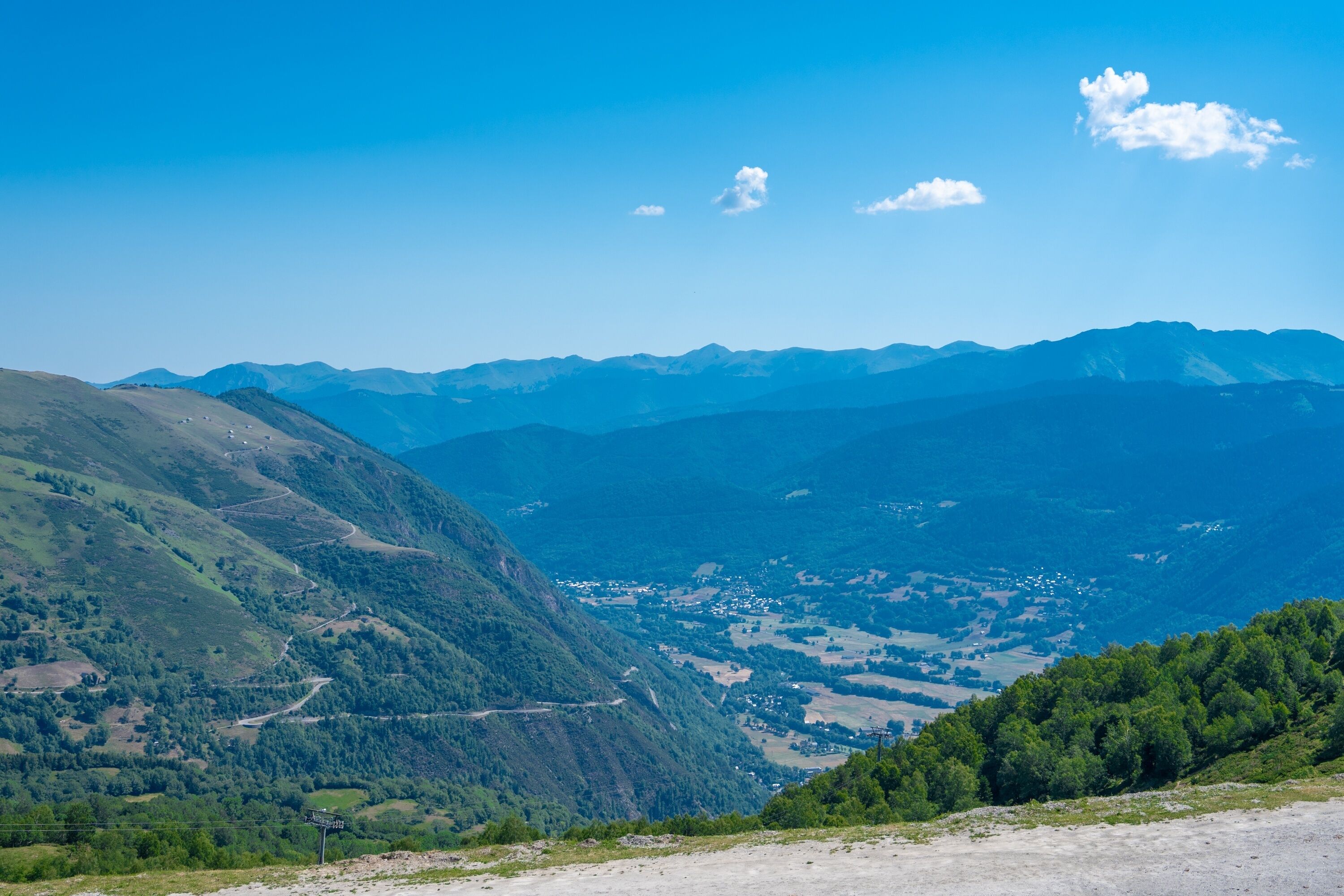 A mountainous landscape with a valley, roads, and scattered buildings.