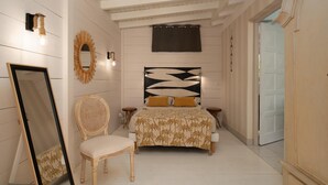 Quarto com cama, uma cadeira, espelho e luminária na parede.