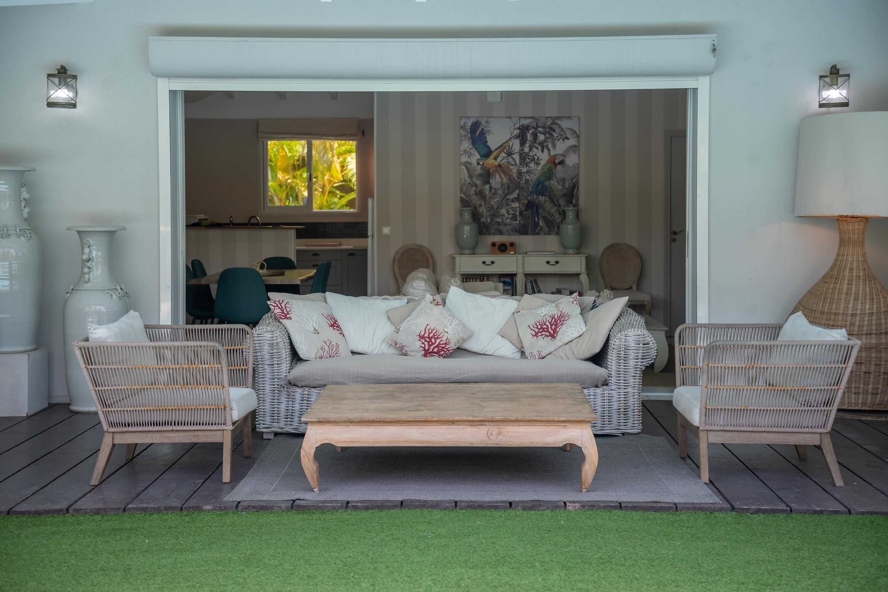 Un espace de vie comprenant un canapé, deux fauteuils en osier, une table basse en bois et une lampe.