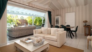 Uma sala de estar ampla, com um sofá branco, uma mesa de centro e um espaço de jantar com cadeiras e uma mesa.