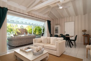 Ein geräumiges Wohnzimmer mit einem weißen Sofa, einem Couchtisch und einem Essbereich mit Stühlen und einem Tisch.