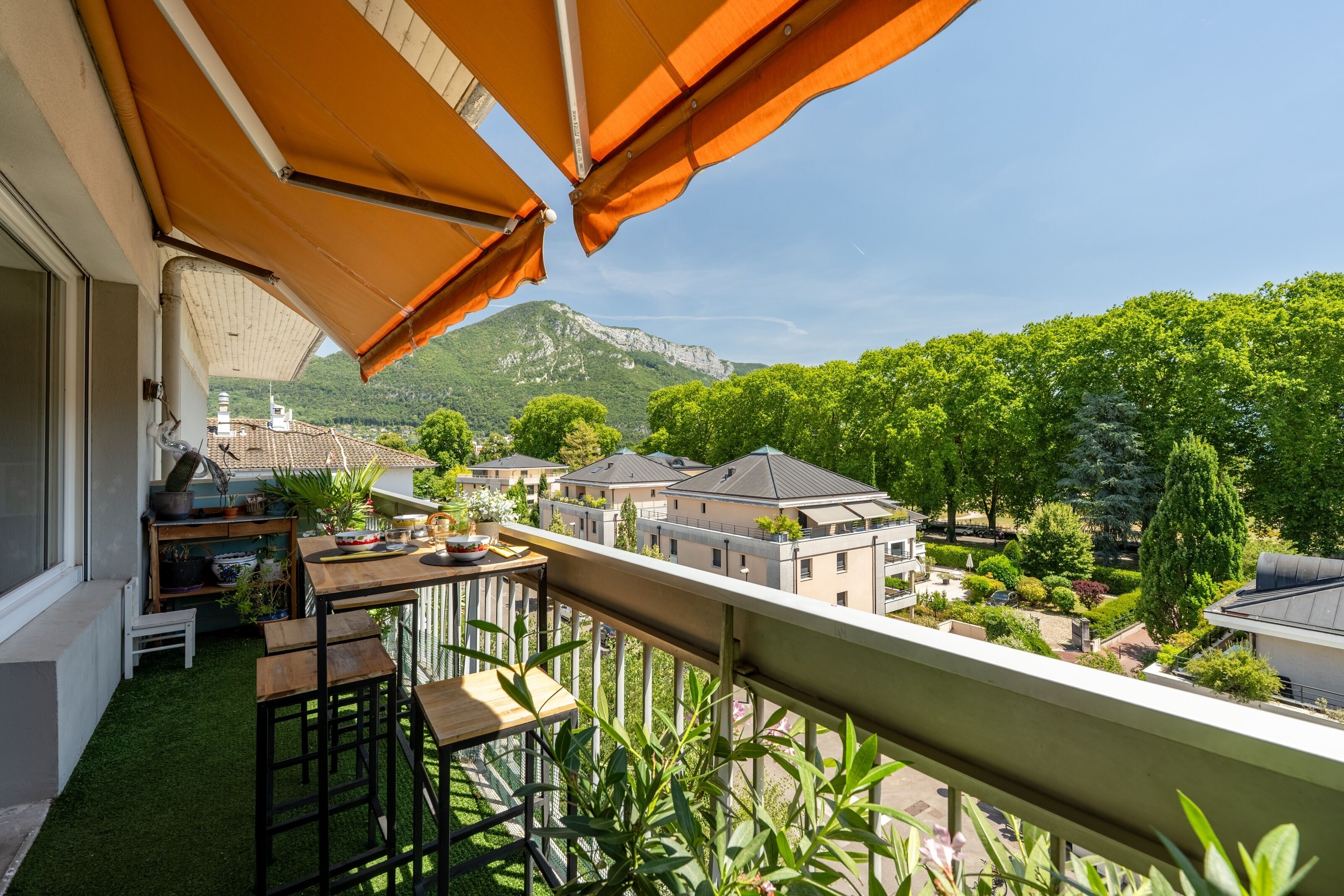 Ein Balkon mit Tisch und Stühlen, Blick auf einen Berg und ein Garten mit verschiedenen Pflanzen.