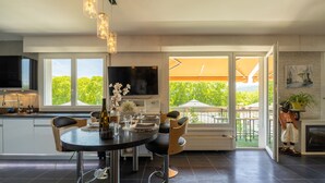 Eine moderne Küche mit Essbereich, einem Fernseher und Blick auf Grünflächen.