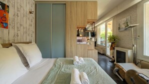 Ein Hotelzimmer mit einem Bett, einem Schreibtisch, einem Sessel, einem Fernseher, einem Kamin und einem Fenster.