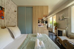 Ein Hotelzimmer mit einem Bett, einem Schreibtisch, einem Sessel, einem Fernseher, einem Kamin und einem Fenster.