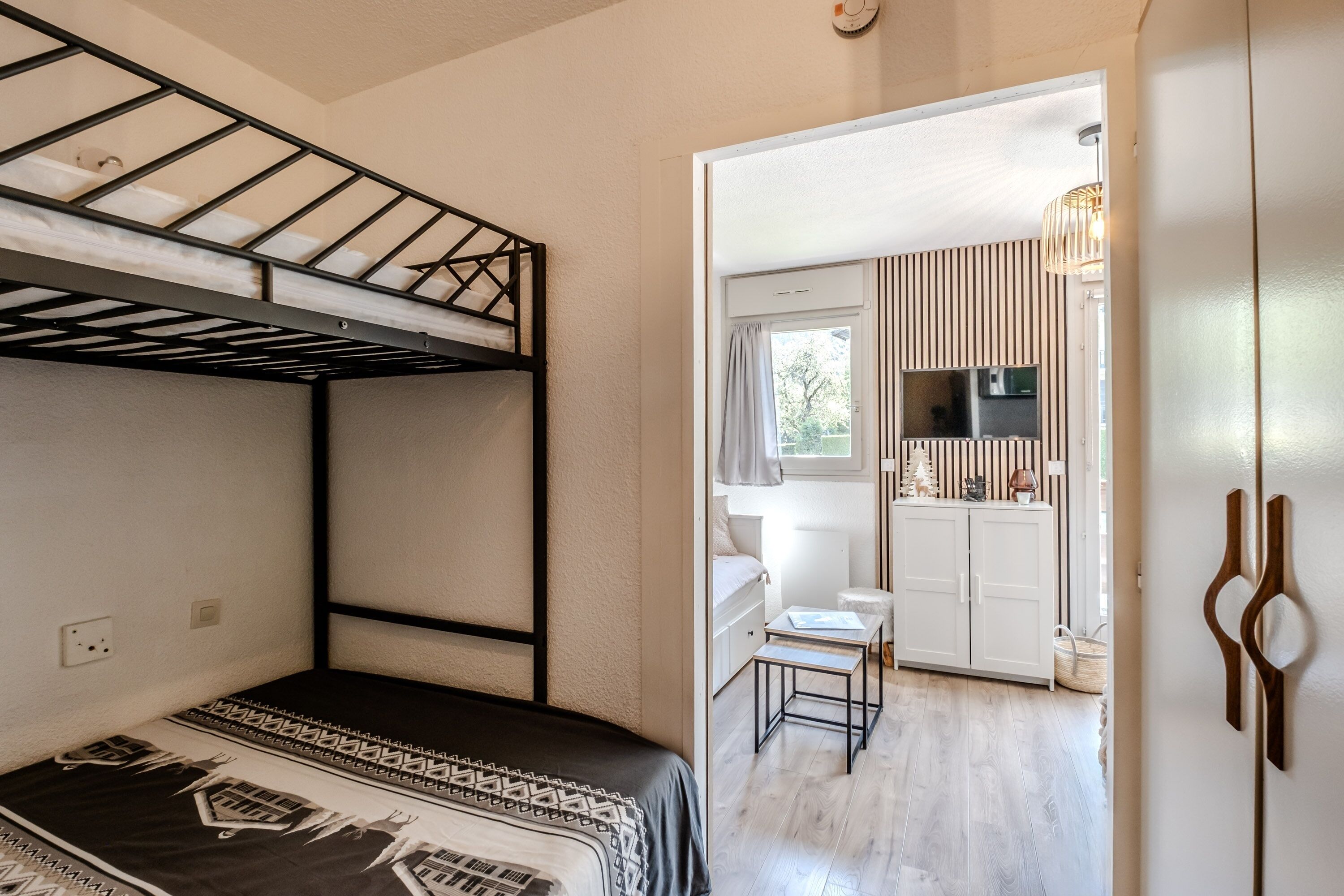 Une chambre avec des lits superposés, un coin cuisine, une petite table et une chaise.