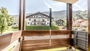 Ein Balkon mit Blick auf ein mehrstöckiges Gebäude, einem Metallgeländer und einer gepflasterten Fläche.