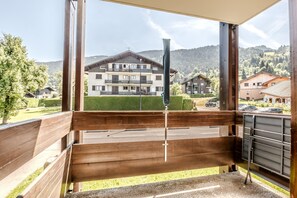 A balcony with a view of a multi-story building, a metal railing, and a paved area. - Le Cocon Montagnard - Studio avec balcon & parking (Arâches-la-Frasse)
