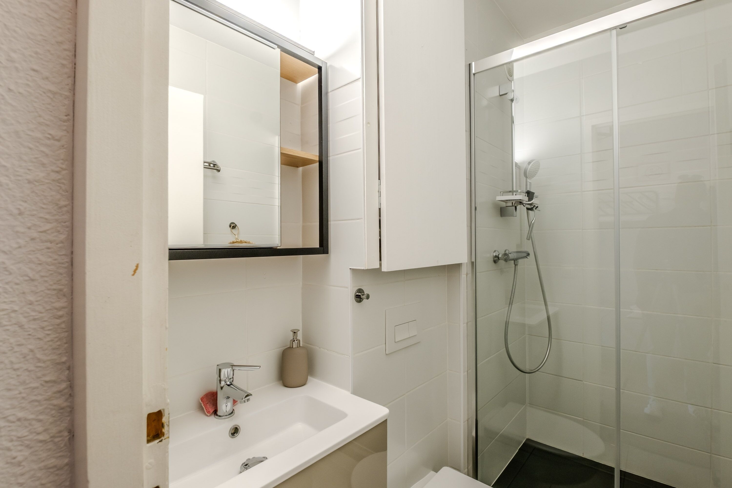 Un baño con lavamanos blanco, espejo y cabina de ducha.