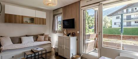 Un salon moderne avec un canapé, une table basse et un téléviseur.