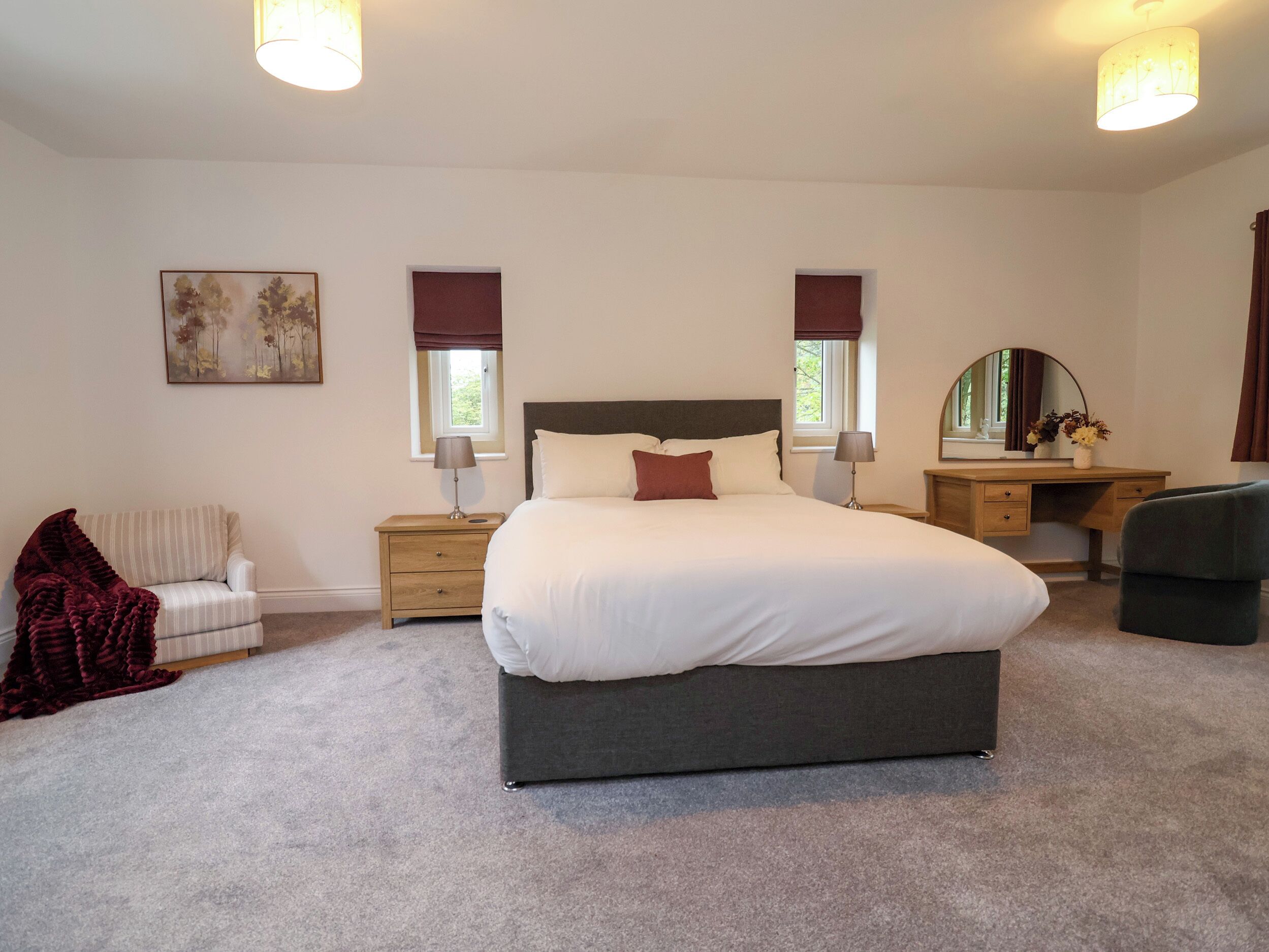 Een slaapkamer met een groot bed, nachtkastjes, een stoel, een bureau en een spiegel.