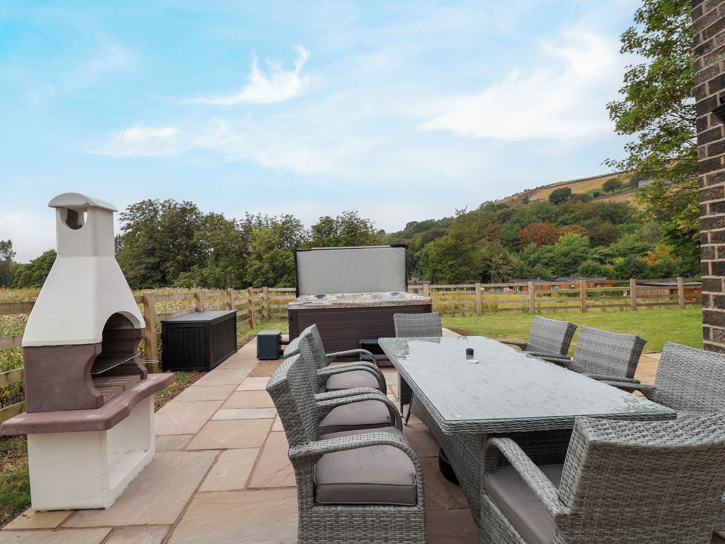 Un patio al aire libre con una parrilla, asientos y un jacuzzi.