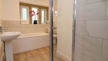A bathroom with a bathtub, sink, and shower area.