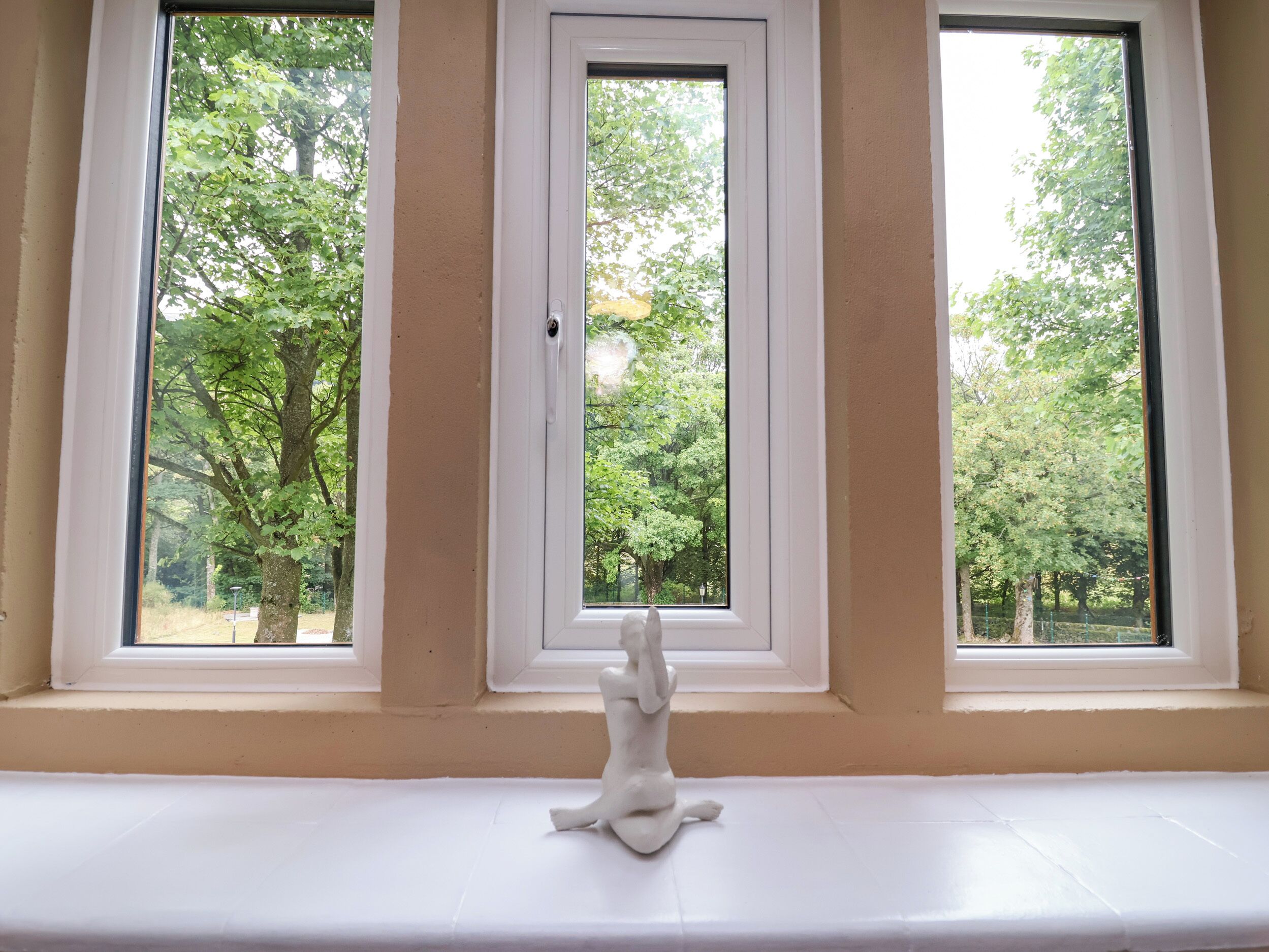 A window with a white sculpture on the sill, framed by beige walls.