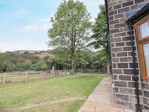 A stone building with a wooden fence and a grassy yard.