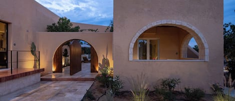A building with arched doorways, a stone pathway, and a landscaped garden.