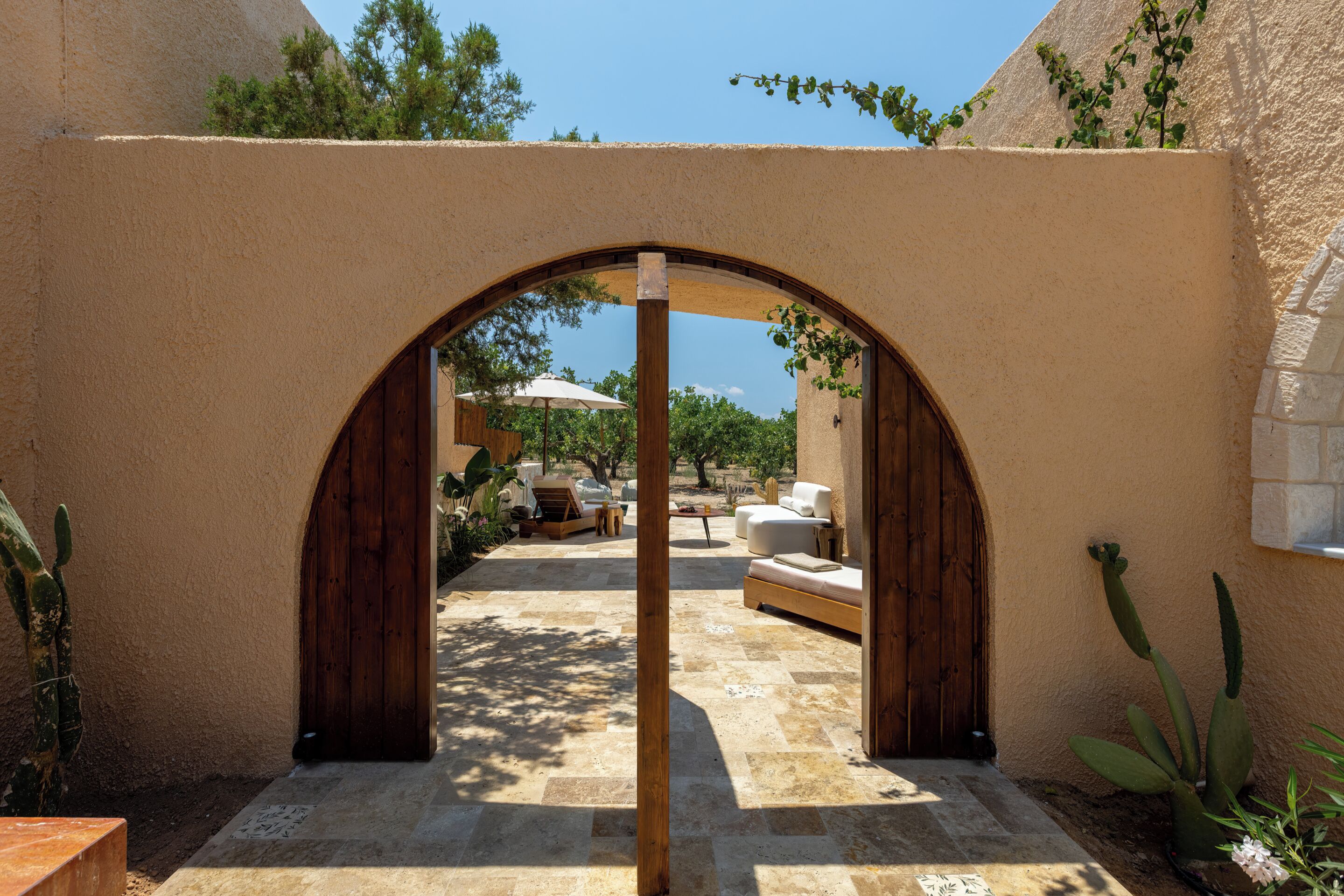 An arched doorway leading to a patio area with outdoor furniture and a view of the surrounding landscape.