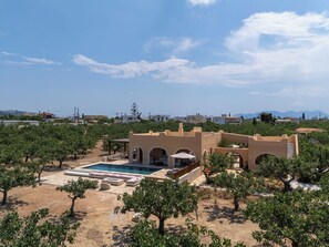 Ein Poolbereich mit einer Pergola, umgeben von Bäumen und einem Gebäude mit Bögen.