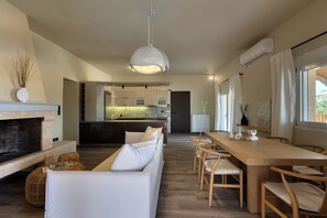 Un salon moderne avec une cheminée, un canapé, une table à manger et des chaises.