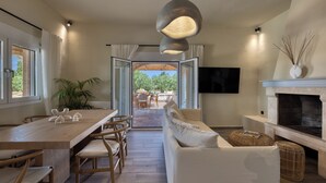 Een modern interieur met een eethoek, bank, open haard en een aan de muur bevestigde televisie.