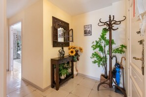A hallway with a wooden console table, a mirror, and a coat rack with a decorative umbrella.